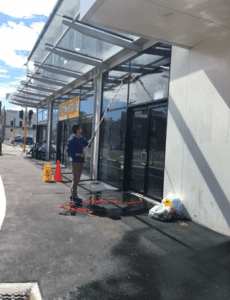 Worker cleaning storefront glass using a water-fed pole