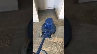 Technician scrubbing hard floors with industrial cleaning equipment.