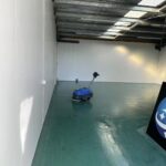 Auto floor scrubber machine cleaning green concrete floor in a Christchurch warehouse