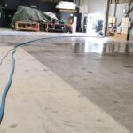 Long blue vacuum hose running through a large warehouse during carpet or floor cleaning