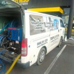 Carpet cleaning van on driveway with long hose running up stairs into home