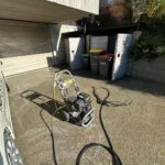 Petrol-powered water blaster on a driveway outside a residential property